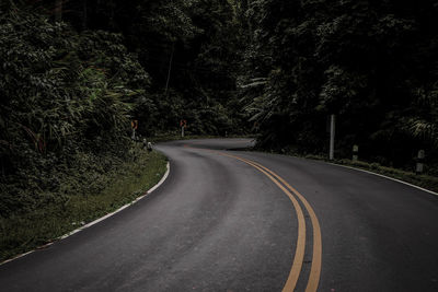 Empty road along trees in forest