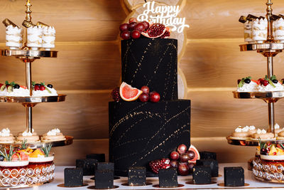 Big black birthday cake with fresh fruits and sweets on a festive table. candy bar. table with 