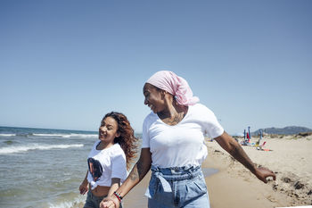 Cheerful black mother and daughter at seaside