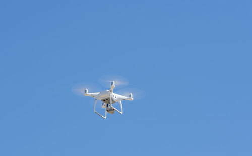 Low angle view of airplane flying against clear blue sky