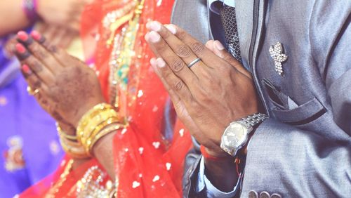 Midsection of couple with hands clasped during wedding 