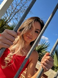 Portrait of woman holding plant against sky