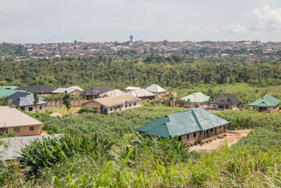 Houses on field by buildings against sky