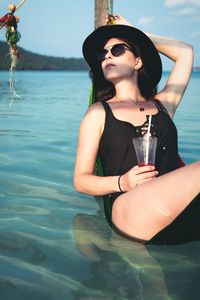 Portrait of smiling young woman standing in lake against sky