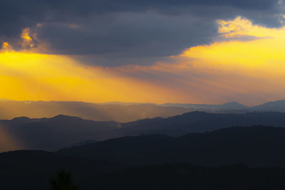 Scenic view of silhouette mountains against orange sky