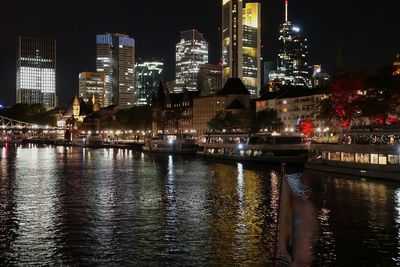 River by illuminated buildings in city at night