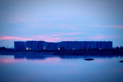 City skyline by river against sky at night