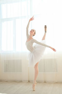 Full length of woman with arms raised standing against wall