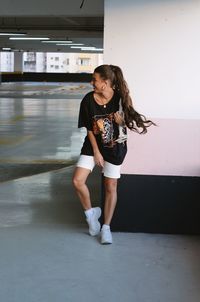 Portrait of smiling young woman standing against wall