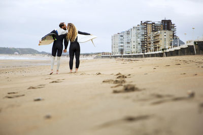 Couple kissing while holding surfboards at beach