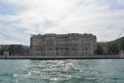 View of building by sea against cloudy sky