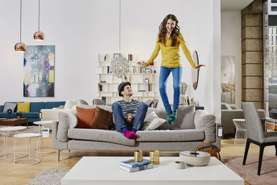 Couple in modern furniture store jumping on couch