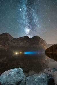 Scenic view of lake and mountains against sky at night