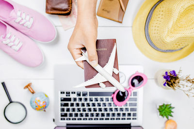 Cropped hand holding model airplane and passport over table