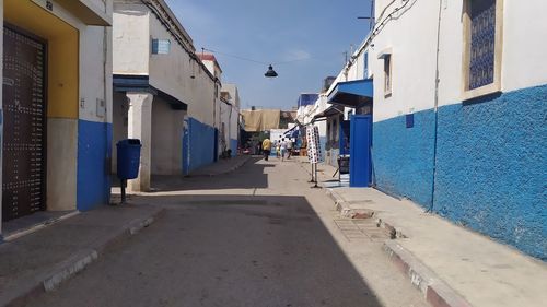 Street amidst buildings against blue sky