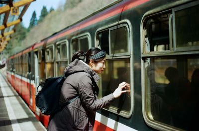 Side view of young woman looking in train window