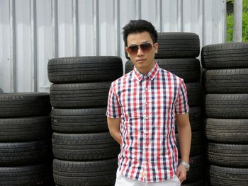 Portrait of young man standing by stack