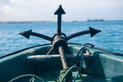 Close-up of rusty wheel by sea against sky