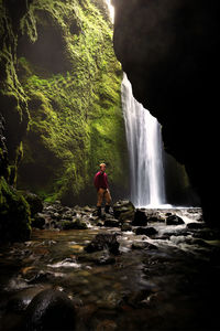 Rear view of man standing against waterfall