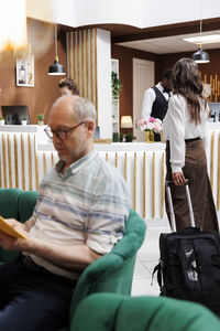 Rear view of man using mobile phone while sitting on sofa at home