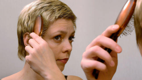 Reflection of woman combing hair on mirror