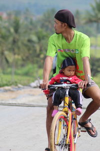 Father riding bicycle with daughter on road
