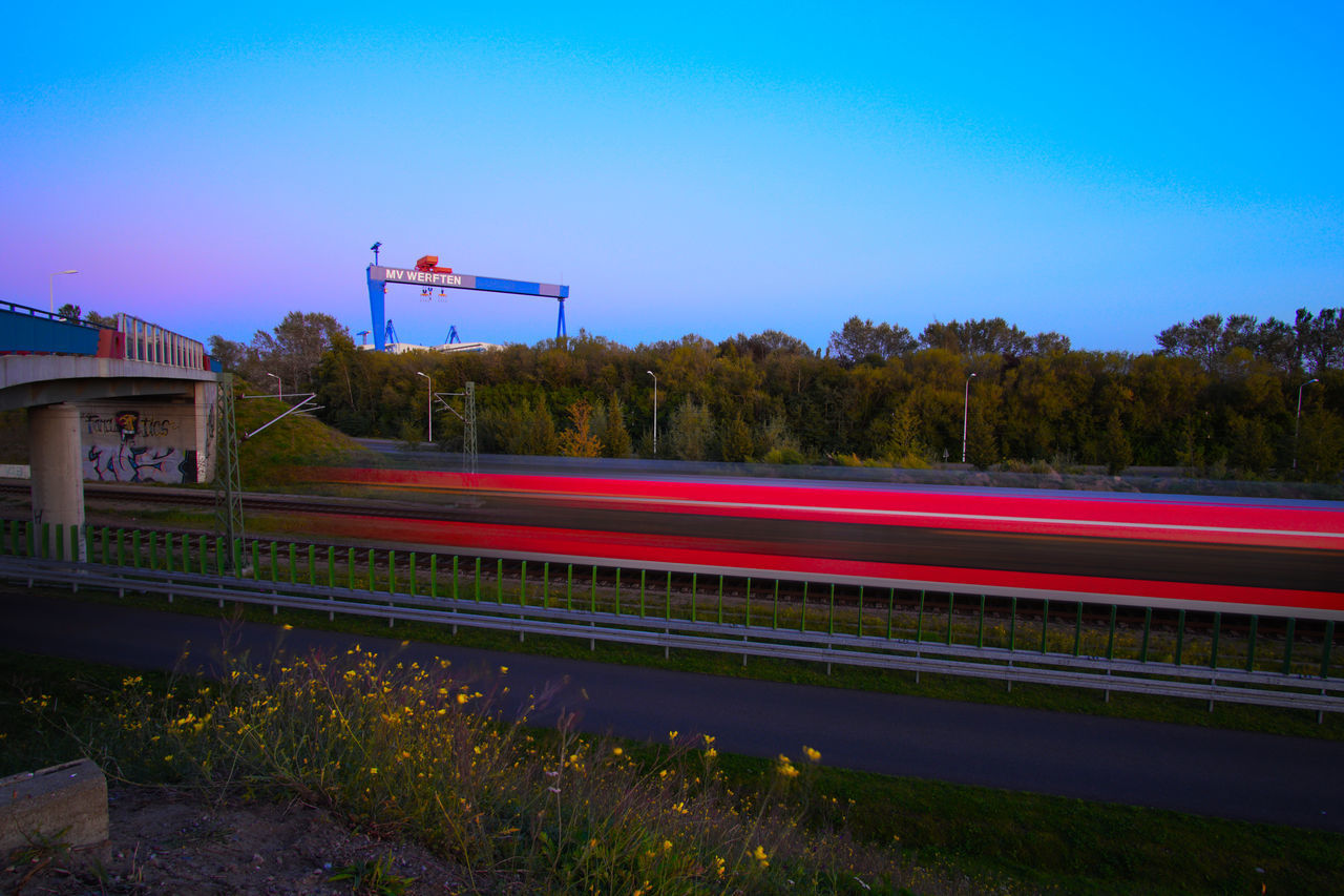 RED LIGHT TRAILS ON ROAD AGAINST BLUE SKY