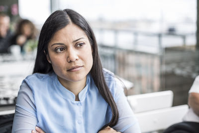 Thoughtful mid adult businesswoman sitting at restaurant