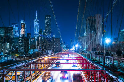 Illuminated bridge and buildings against sky at night