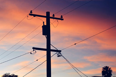 Low angle view of silhouette electricity pylon against sky during sunset