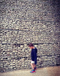 Boy standing by fence