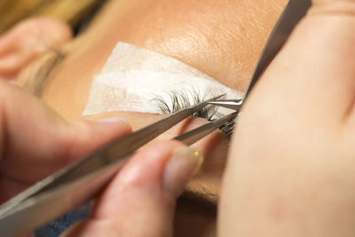 Close-up of beautician applying false eyelash to customer