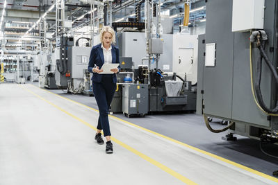 Businesswoman using tablet pc walking at modern factory