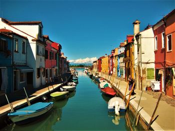 Boats moored in canal amidst buildings in city