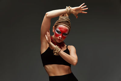 Portrait of young woman standing against black background