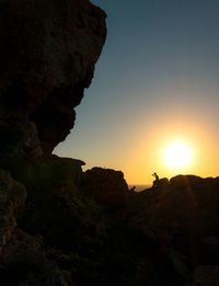 Silhouette rock formations against sky during sunset