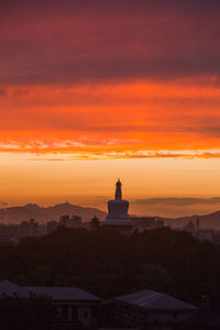 Silhouette of building against cloudy sky during sunset