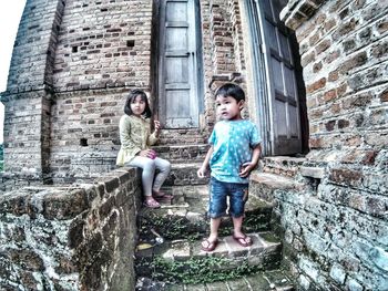 Full length portrait of boy standing against house