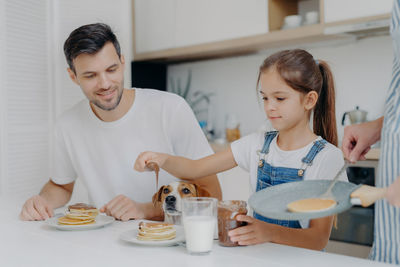 Man looking at girl putting chocolate spread on pancakes