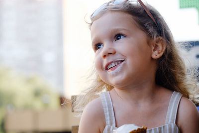 Toddler child eating cone ice cream outside near cafe. cute blonde caucasian girl licking frozen