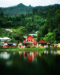 Houses by lake and trees against plants