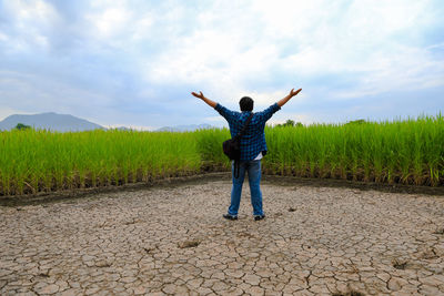 Rear view of man standing on field against sky