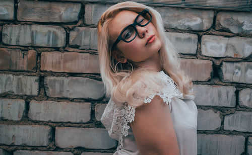 Portrait of young woman posing against brick wall