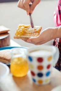 Cropped image of woman spreading orange jam on bread at home
