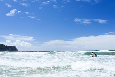 People in sea against sky