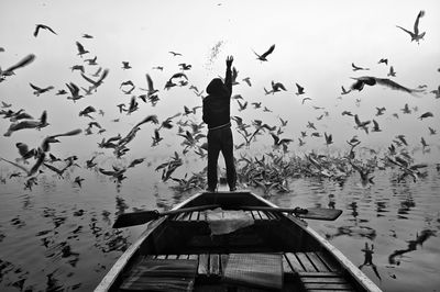 Rear view of man standing in boat on lake