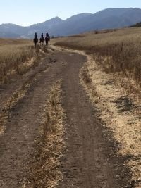 People walking on landscape against sky