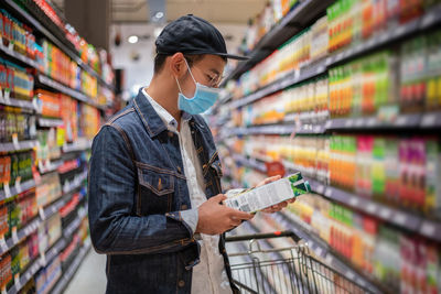 Man wearing mask buying groceries in supermarket