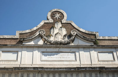 Low angle view of statue against building against clear blue sky