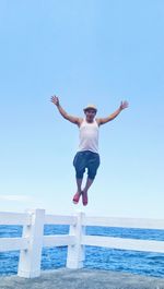 Full length of man jumping by sea against clear sky
